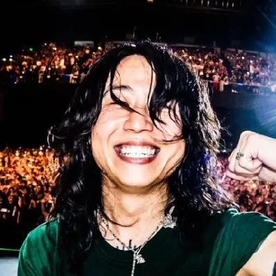 Tomoya smiling behind the drum kit during a lively ONE OK ROCK concert
